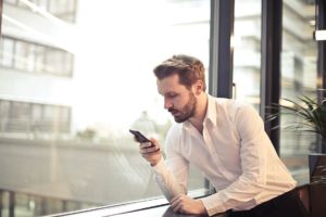 A person standing next to a window with a phone calling someone

Description automatically generated